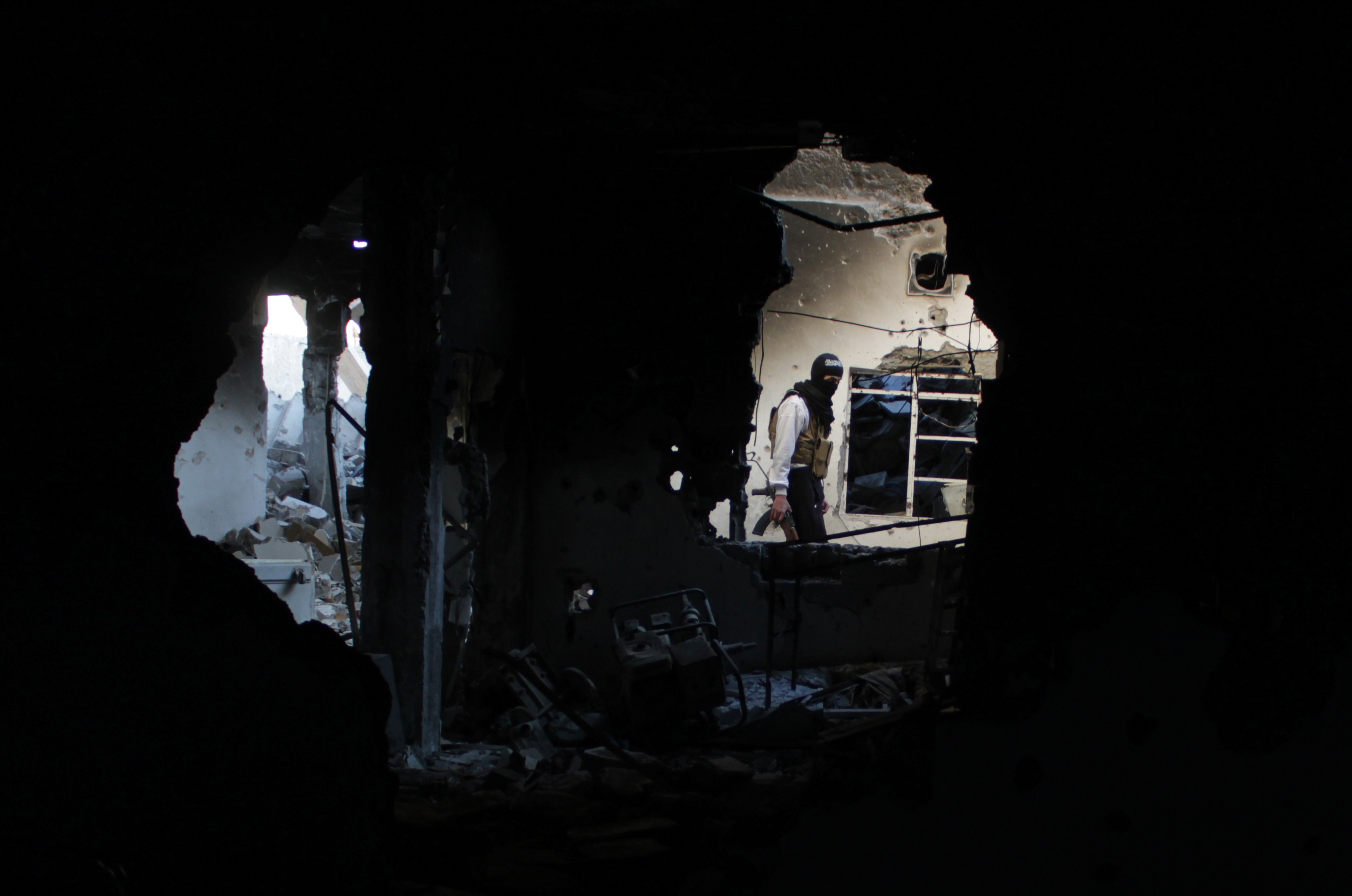 Un miliciano rebelde camina entre los restos de un edificio dañado por la aviación siria en Deir Ezzor, en el noreste del país