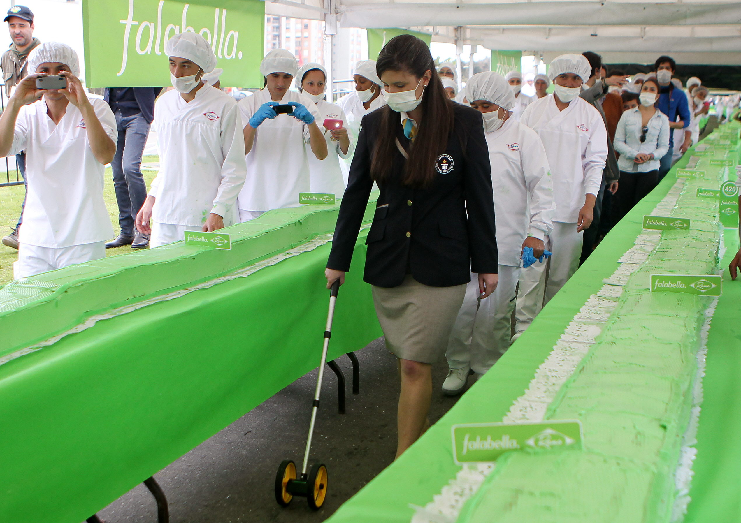 Una delegada de Guinnes Record mide un pastel de 606 metros antes de confirmarlo como nueva marca.