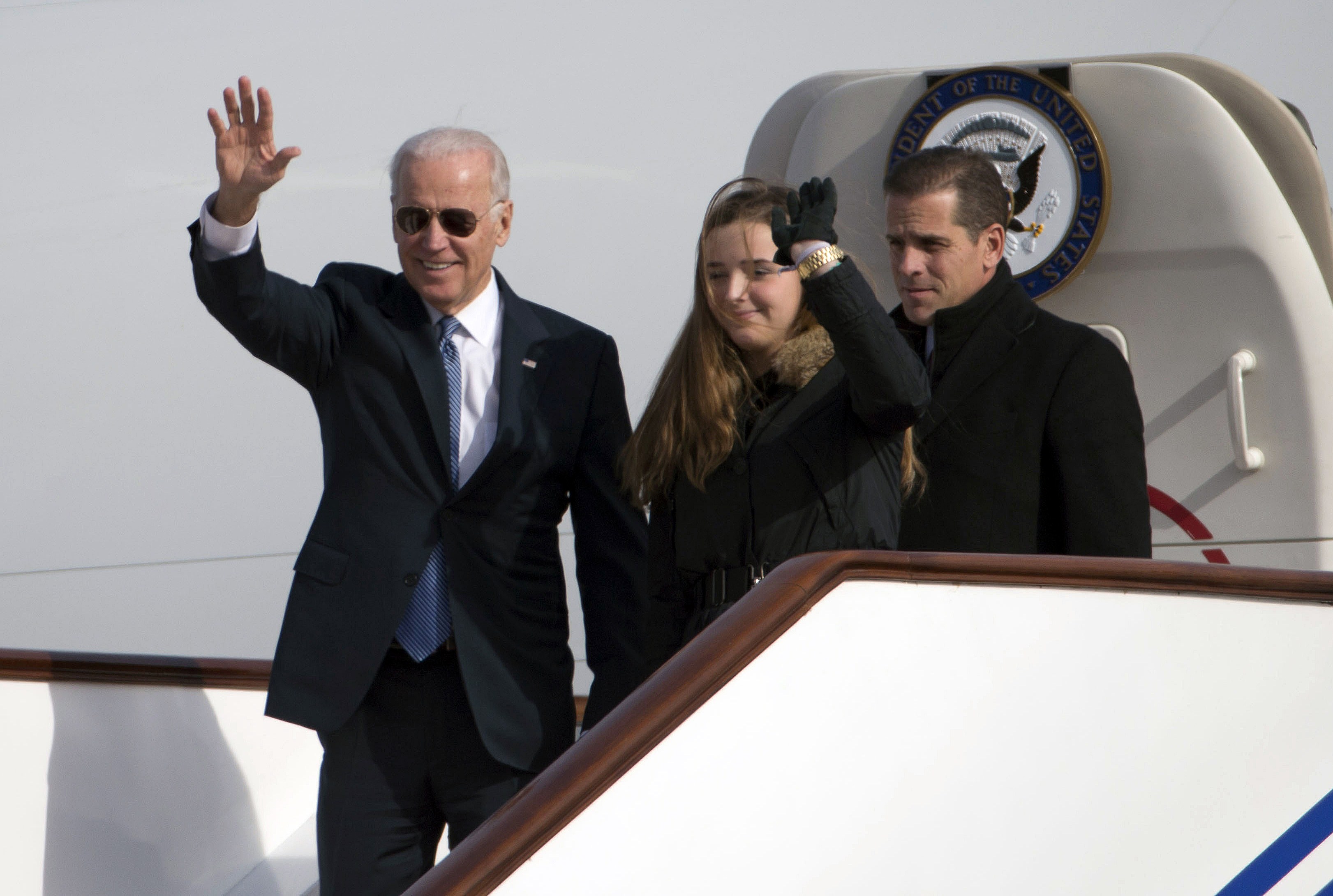 Biden saluda al salir del Air Force Two en Pekín junto a su nieta, Finnegan Biden (c) y su hijo Hunter Biden (d) 