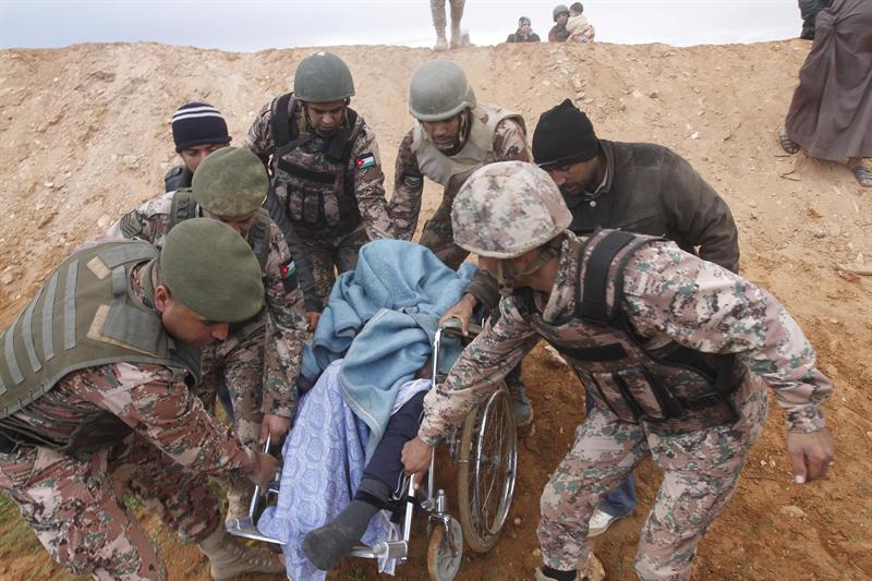 Soldados jordanos ayudan a un refugiado sirio enfermo a su llegada al este de la frontera entre Siria y Jordania, en Royashed