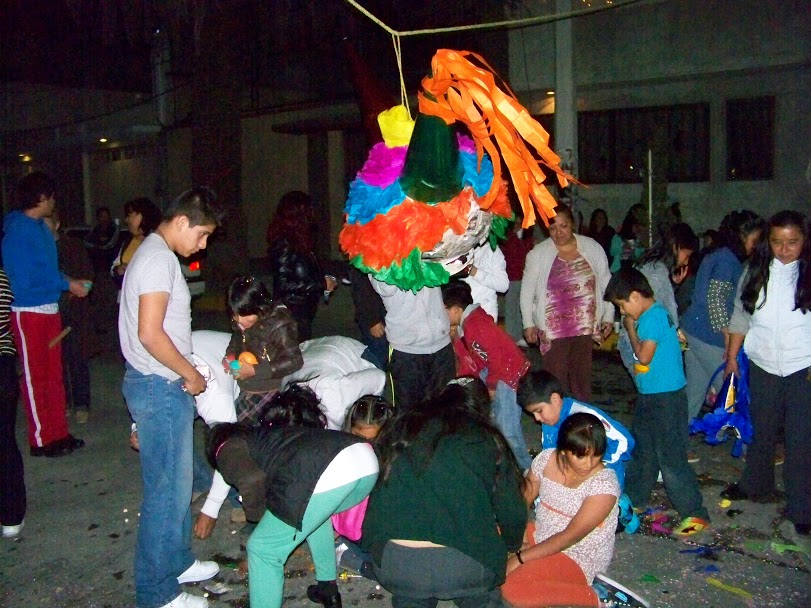 Niños y adultos se lanzan a recoger el contenido de la piñata esparcido en el piso.