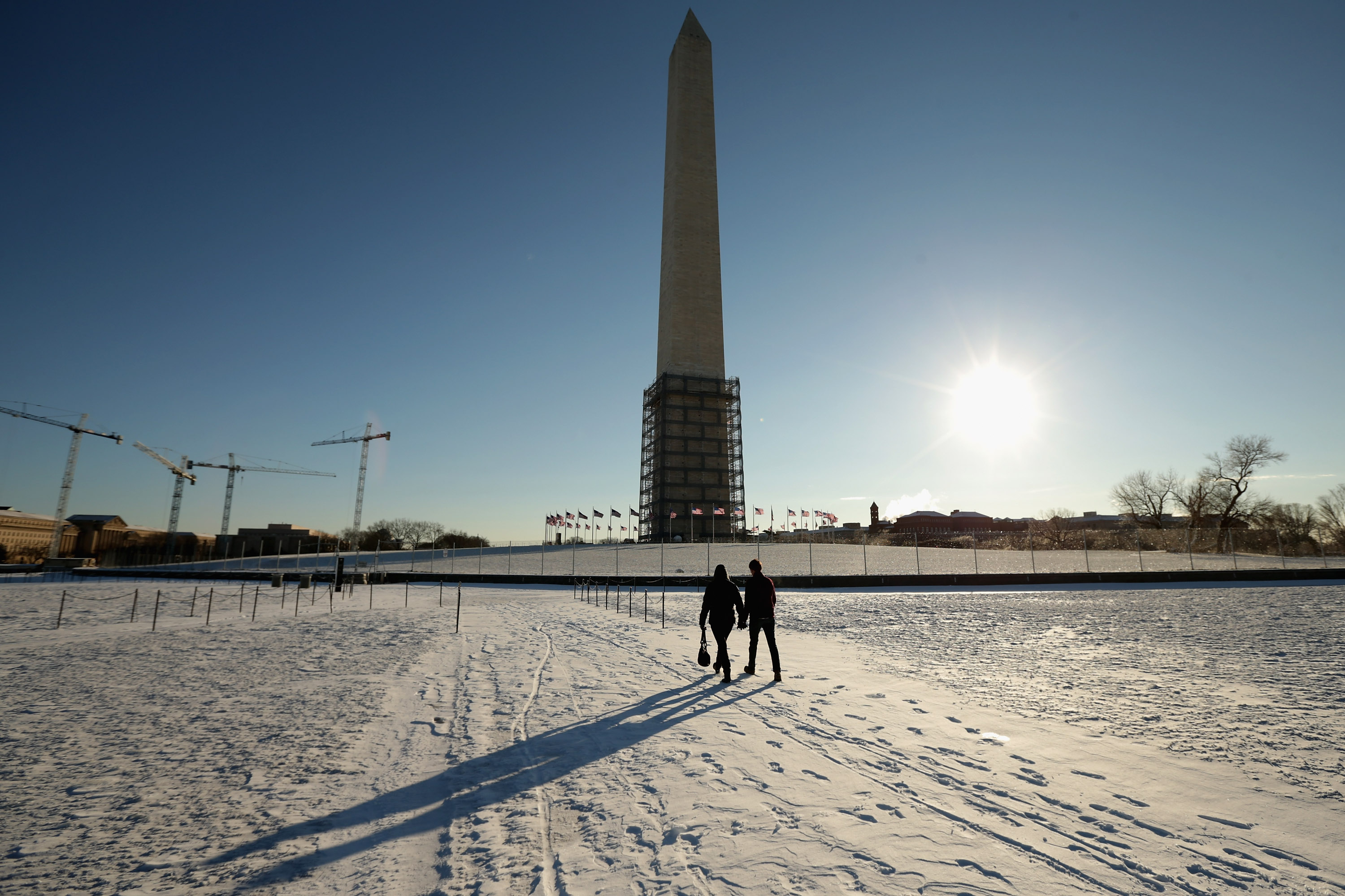Los turistas caminan en la nieve cerca de la base del Washington Monuement 