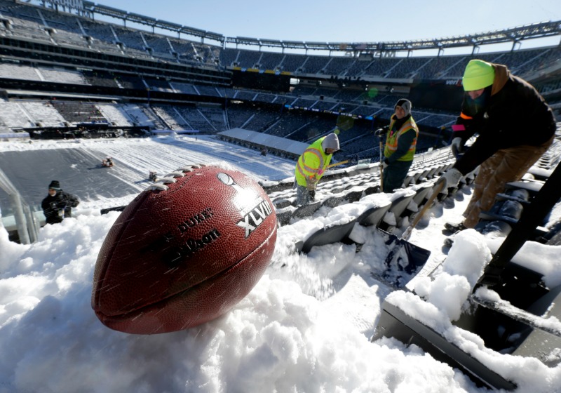 Un balón con el logo del Super Bowl XLVIII es fotografiado mientras trabajadores retiran la nieve del Metlife.