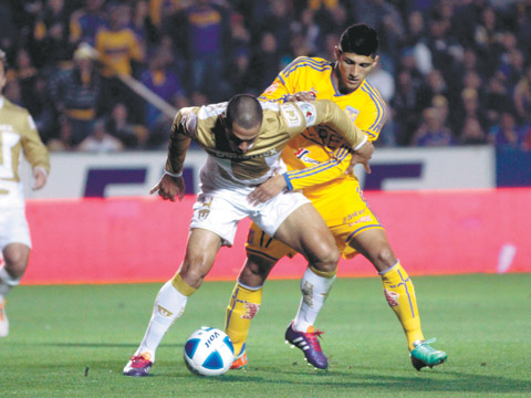 Alan Pulido pelea un balón con Darío Verón.