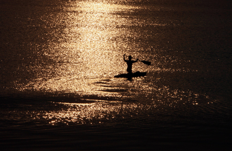 Un deportista práctica en canoa mientras el sol se pone en el lago Hussain Sagar en Hyderabad.