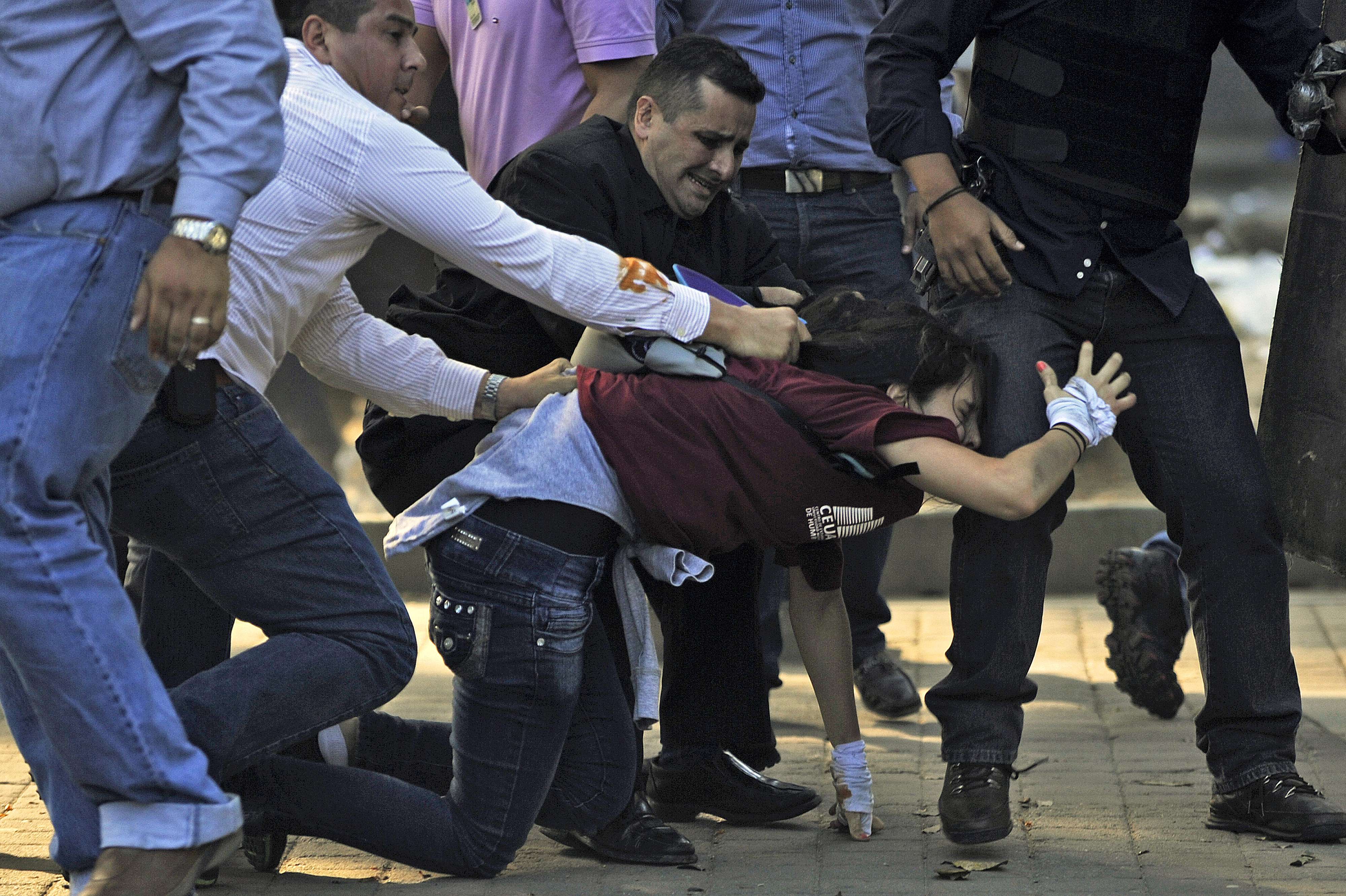 Agentes de la CICPC (Policía Científica) venezolana detienen a una estudiante durante la manifestación del miércoles en Caracas