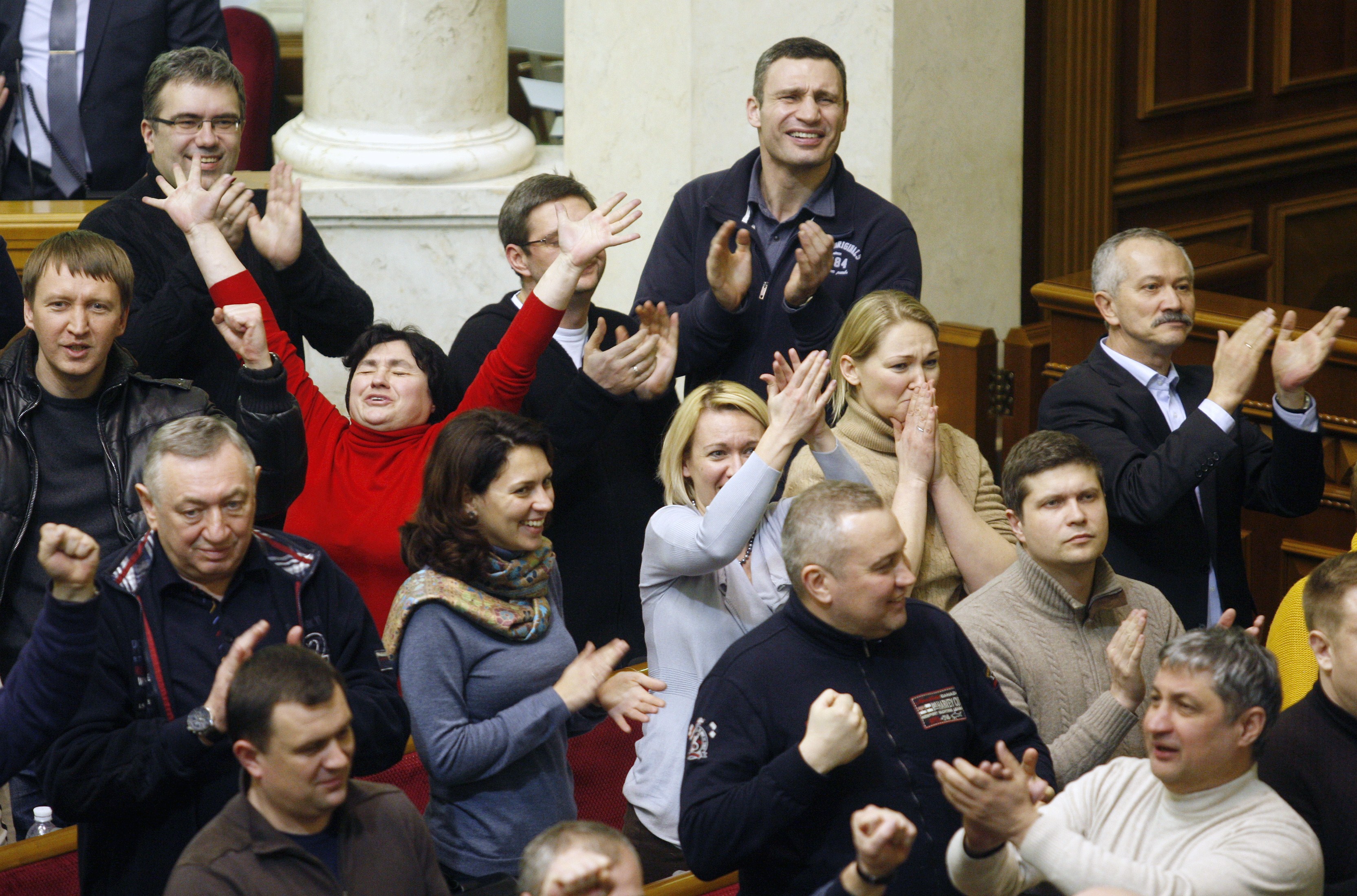 El líder del partido opositor UDAR (Puño) Vitali Klitschko (derecha, detrás) y diputados de su grupo aplauden la votación para acabar con la represión