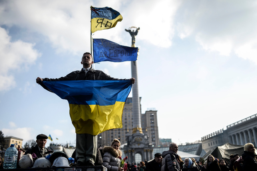 Un hombre exhube una bandera en la Plaza de la Independencia de Kiev, donde se emitió una orden de arresto para derrocado presidente Viktor Yanukovich