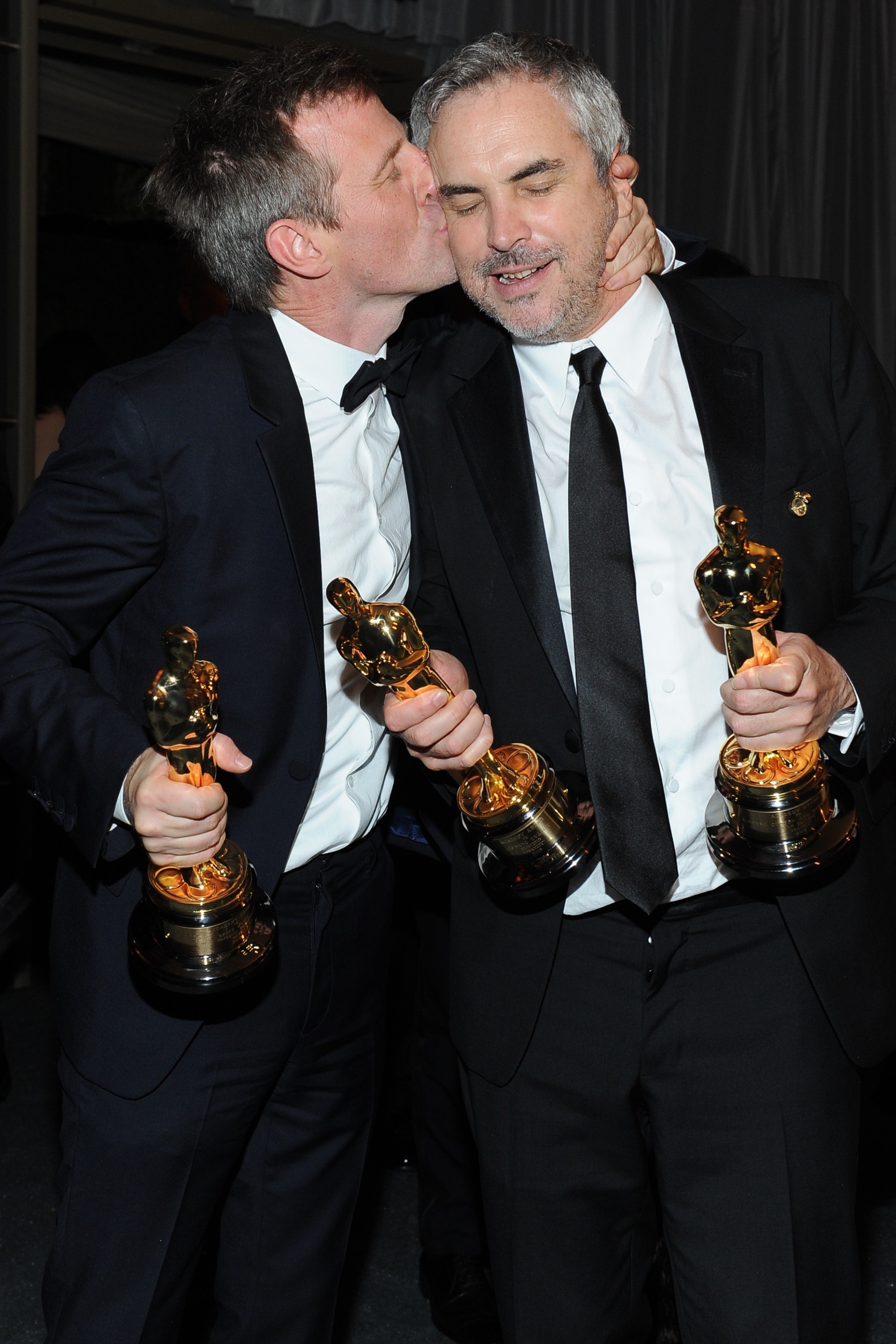 El director de 'Her', Spike Jonze, da un beso al cineasta mexicano Alfonso Cuarón durante la fiesta del Governador celebrada después del Oscar.