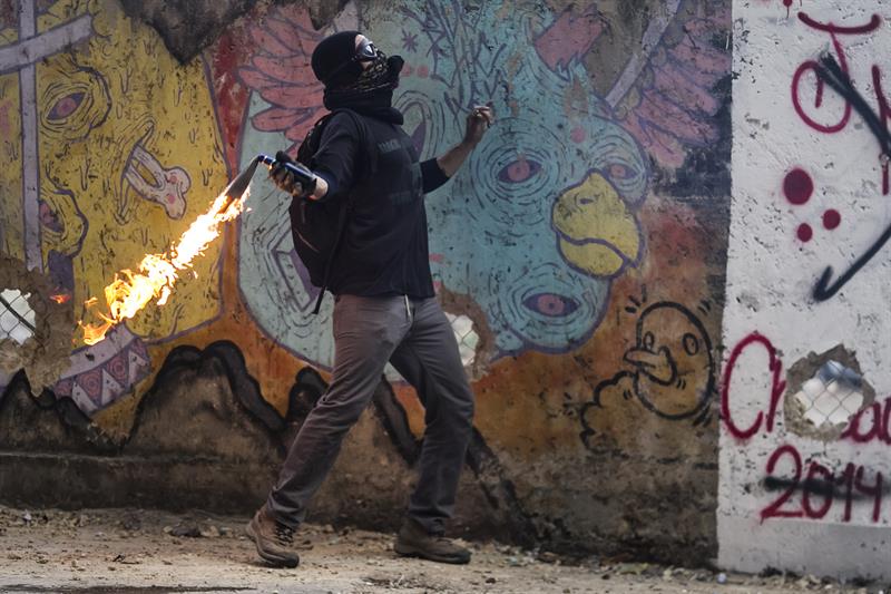 Un manifestante se enfrenta a integrantes de la Policía Nacional Bolivariana hoy en Caracas
