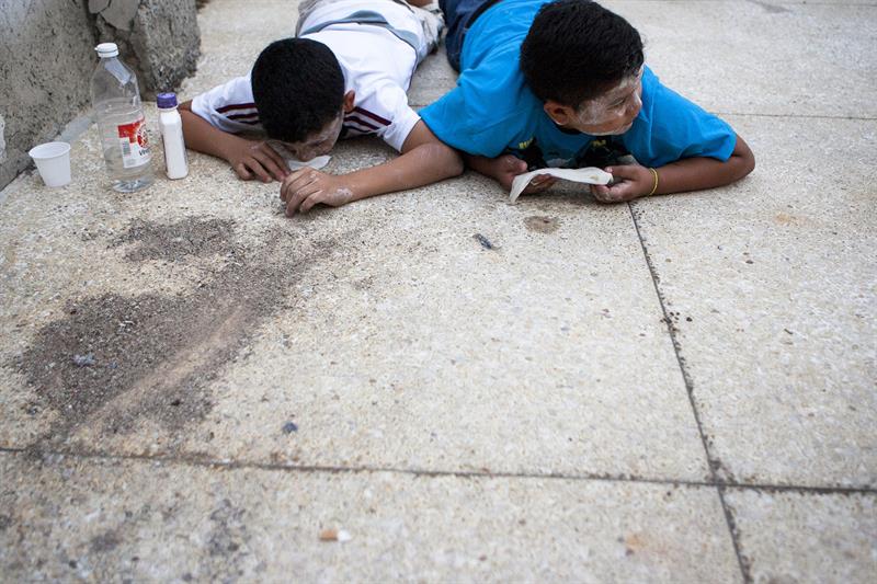 Dos niños se protegen de las bombas lacrimógenas hoy cerca de la Plaza Altamira de Caracas 