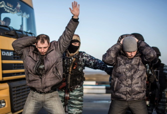 Hombres se llevan las manos a la cabeza mientras son revisados por milicianos prorrusos en el puesto de control de Chongar, en Crimea