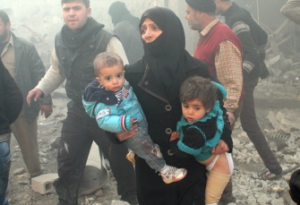 Una mujer siria lleva en sus brazos a dos niños tras un bombardeo en la ciudad de Alepo, en el norte del país
