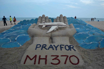 Una escultura de arena relativa al avión desaparecido, en que se pide rezar por los pasajeros, en la playa de Puri, en la India