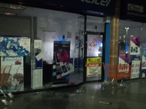 Normalistas rompen vidrios de una tienda de la Plaza Oaxaca.