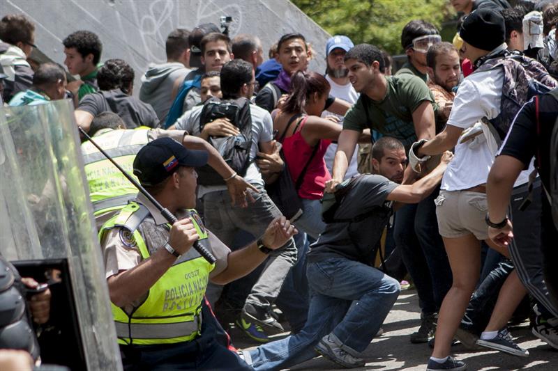 Manifestantes opositores se enfrentan a miembros de la Policía Nacional Bolivariana (PNB) tras una concentración hoy en Caracas