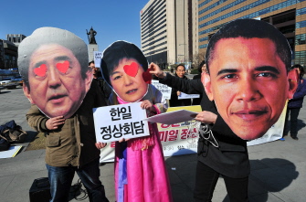 Activistas surcoreanos con máscaras de la presidenta Park Geun-Hye (c) el primer ministro nipón Shinzo Abe (i) y Obama (d), en Seúl 