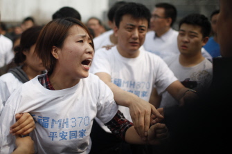 Una de las familiares de las víctimas chinas del vuelo de Malaysia Airlines grita a un agente policial ante la embajada malasia en Pekín 