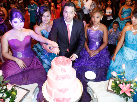 El secretario de Desarrollo Social parte el pastel acompañado de varias quinceañeras.