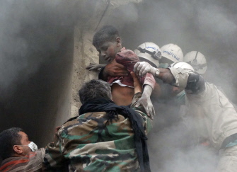 Trabajadores de ayuda de emergencia ayudan a evacuar a un niño sirio de un edificio bombardeado por un helicóptero del ejército en Alepo 