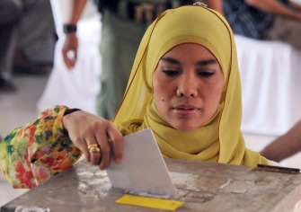 Una mujer indonesia deposita su voto en una urna en un centro electoral en Yakarta
