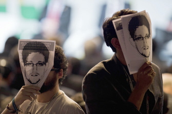 Activistas muestran máscaras de papel con el rostro del ex analista de la NSA Edward Snowden durante la apertura de la cumbre en Sao Paulo