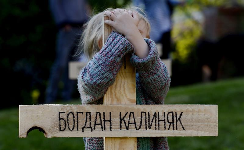 Un niño abraza una de las 107 cruces colocadas en memoria de los muertos en las recientes protestas en Kiev en Praga, República Checa