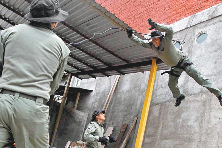 Tres guardias de la nueva fuerza de seguridad realizan una práctica de rapel.