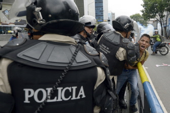 Policías antidisturbios arrestan a un estudiante venezolano durante una protesta hoy en Caracas