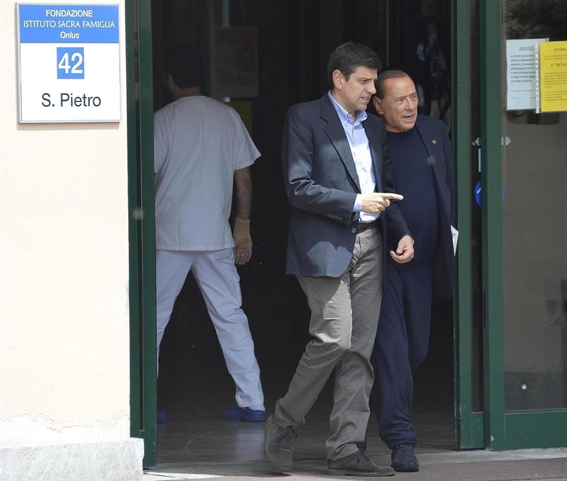  El ex primer ministro italiano Silvio Berlusconi abandona el centro de la Fundación Sagrada Familia acompañado por el responsable de ese mismo centro