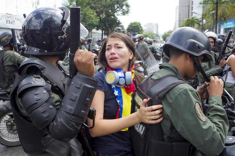Una manifestante es detenida por miembros de la Guardia Nacional Bolivariana (GNB) durante una marcha hoy en Caracas