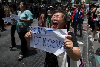 Un manifestante muestra su indignación contra el golpe militar gritando a los soldados mientras sostiene una pancarta que dice "queremos democracia" 