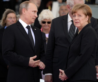 El presidente ruso, Vladimir Putin, y la canciller alemana, Angela Merkel, conversan durante la conmemoración del Día D, en Ouistreham, Normandía