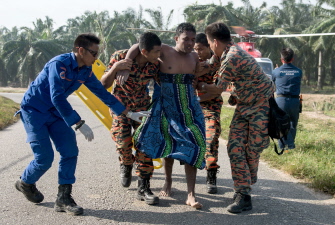 Un equipo de rescatistas malayos ayuda a una víctima (c) del naufragio rescatada del barco hundido en Kelanang Jetty, cerca de Banting