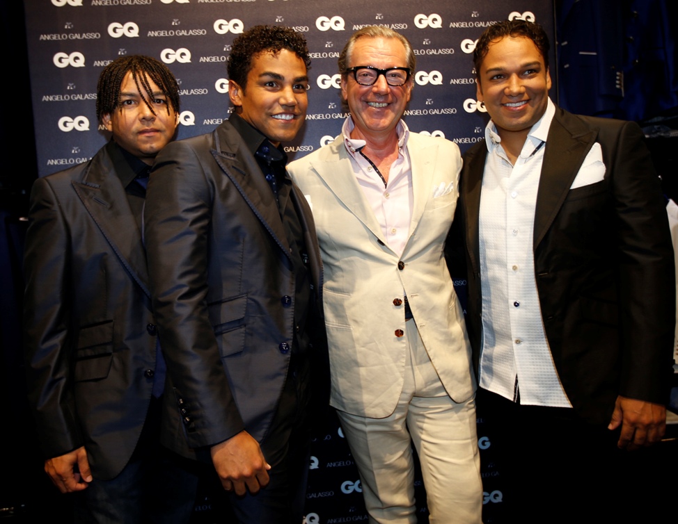 El grupo pop 3T Taj, TJ y Taryll, quienes posan con el diseñador italiano Angelo Galasso durante un evento de la semana de la moda en Milan. 