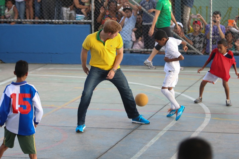 Vestido con una camiseta con los colores de Brasil, el príncipe Enrique jugó una pachanga con algunos niños. 