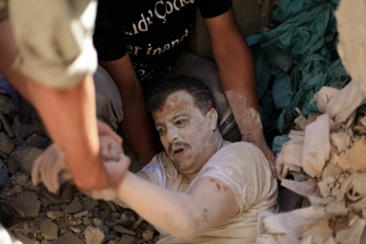 Miembros de la Defensa Civil Siria rescatan a un hombre de los restos de un edificio después de un ataque aéreo del ejército sirio en Alepo