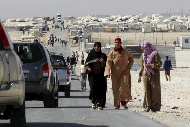 Mujeres sirias ven pasar a un convoy de la ONU en el campo de refugiados de Zaatari, en Jordania