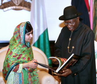 La activista paquistaní Malala Yousafzai (i) mira el libro que le enseña el presidente de Nigeria, Goodluck Jonathan, en Abuja