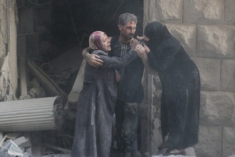Varios sirios se abrazan entre el polvo tras un bombardeo de la aviación siria en Alepo