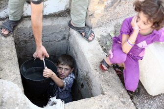 Un niño sirio extrae agua de un pozo en la ciudad de Duma, cerca de Damasco