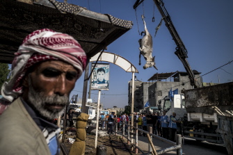 Un grupo de palestinos miran como es retirado el cadáver de un burro muerto en el ataque israelí a una escuela de la ONU 