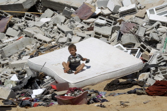 Un niño palestino descansa junto a los escombros de una casa destruida en un ataque aéreo israelí en Abasan, al este de Khan Yunis