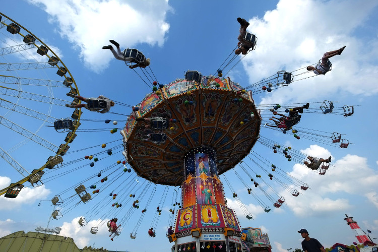Decenas de personas se divierten en los juegos de la feria  "Cranger Kirmes", en Herne.