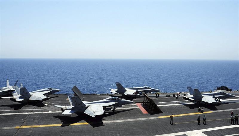 Miembros de la Marina guian a varios aviones Hornet F/A 18 para su despegue en el portaaviones George H.W. Bush, en el Golfo Pérsico 