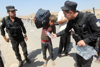 Milicianos kurdos ofrecen botellas de agua a refugiados de la comunidad Yazidi al cruzar la frontera sirio-iraquí en Fishkhabur, en el norte de Irak
