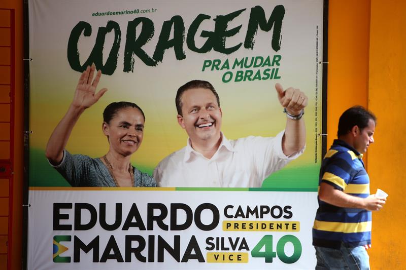 Un hombre camina junto a un cartel con la imagen de Campos y Silva, en Recife, donde la sede de campaña del candidato está de luto  