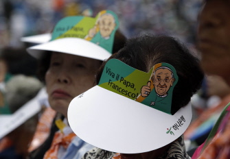 Fieles católicos, con gorras de cartón con la figura del Papa Francisco, durante la misa en el Daejeon World Cup Stadium 