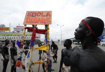 Artistas del grupo "'Be Kok Spirit'' sostienen un cartel que dice "Ebola, véte" como parte de una campaña en Abidjan, Costa de Marfil