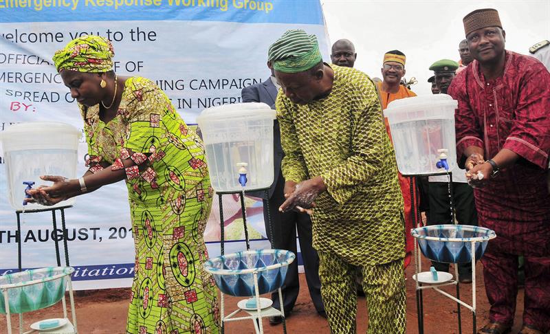 La ministra nigeriana de Recursos del Agua, Sarah Ochee (i), se lava las manos en una campaña nacional contra el ébola en Abuja